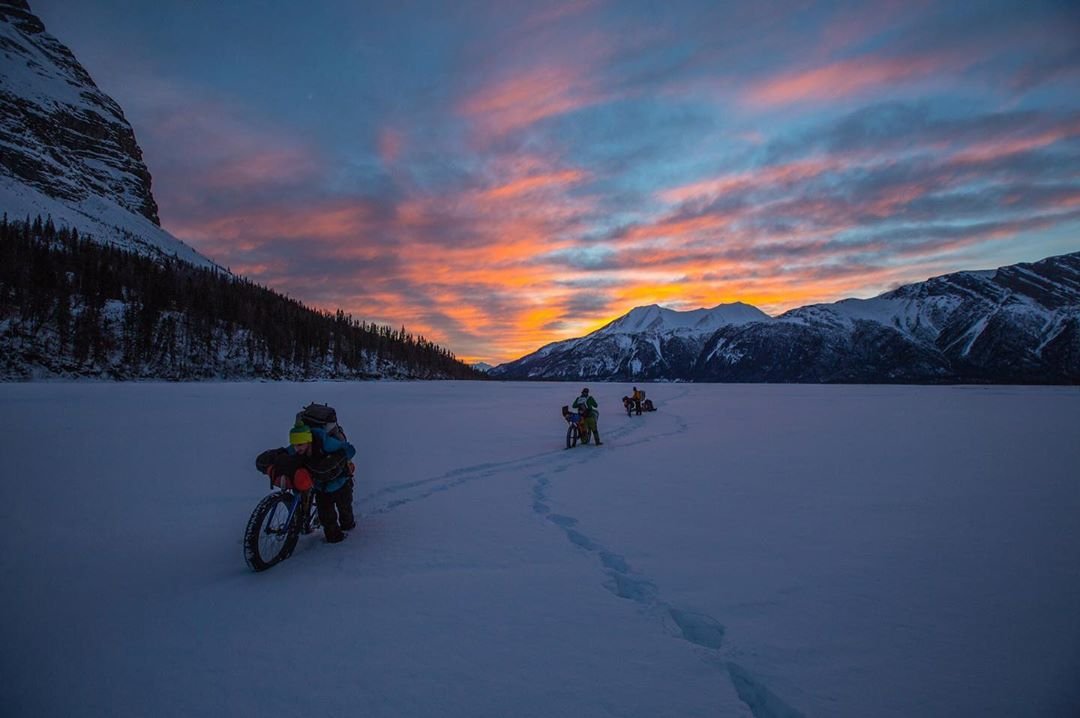 A few extreme outdoor cyclists packing their bikes through a frozen, snow covered tundra
